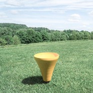 A solitary golf bunker on the green golf course, surrounded by gentle hills and trees in the background.
