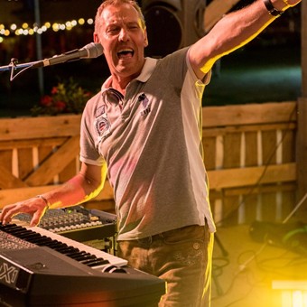 Musiker Joe Böhm singt und spielt Keyboard bei einem Auftritt.