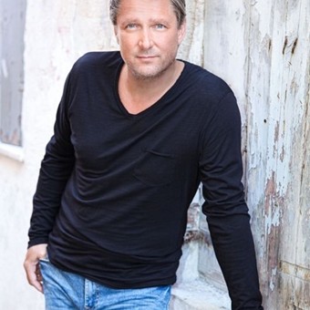 Musiker Marco Schelch, der an einer Wand lehnt und in die Kamera blickt.