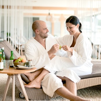 Couple in bathrobes relaxing together on a lounger in the spa's quiet area.
