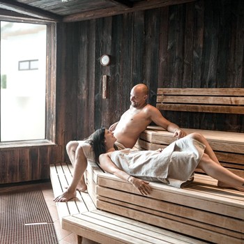 Zwei Gäste entspannen in der Sauna des Allegria Resort Stegersbach im stilvollen Wellnessbereich.