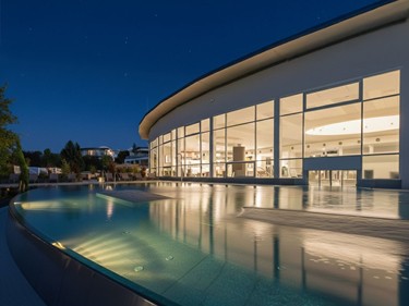 beleuchteter Infinity Pool am Abend vor der Therme Stegersbach mit Blick in den Sternenhimmel.