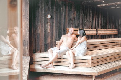 Soothing tranquillity for your time off A couple relaxes in the cozy warmth of a rustic wooden sauna in the sauna world, while soft lighting creates a calming atmosphere.