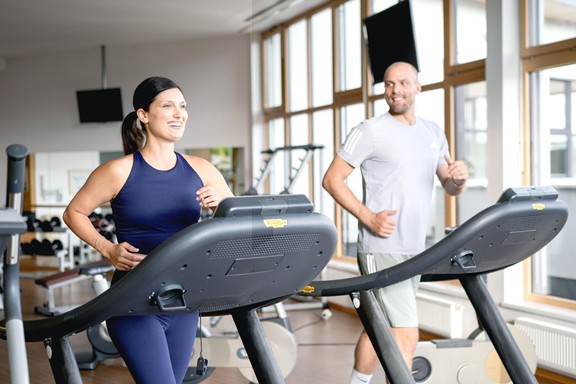 Stay active with a view of nature Couple working out on treadmills in the panoramic fitness room at Allegria Resort.